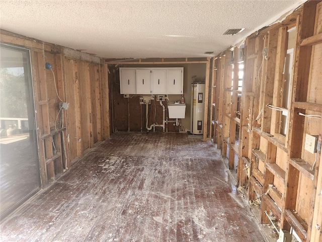 misc room with a textured ceiling, electric water heater, and sink