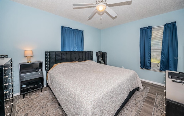 bedroom with a textured ceiling, wood-type flooring, and ceiling fan