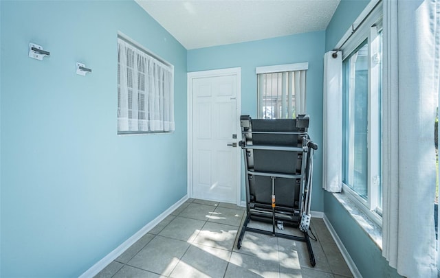 doorway with a textured ceiling, a wealth of natural light, and tile patterned flooring