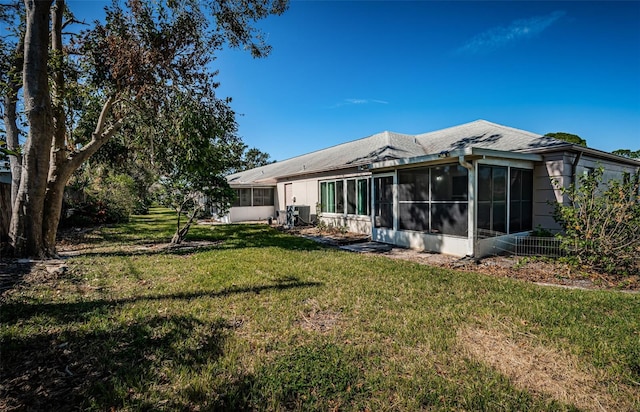 back of house featuring a lawn and a sunroom