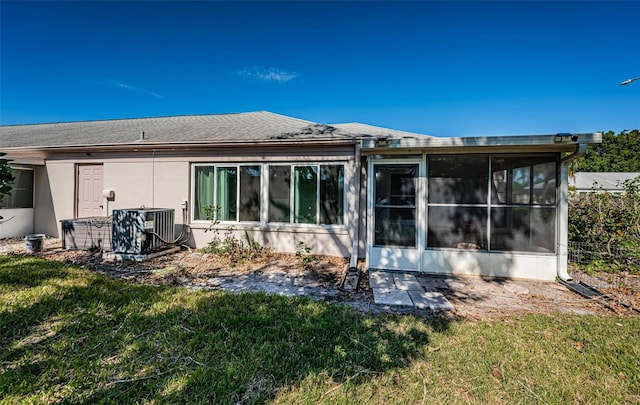 back of house with central AC, a lawn, and a sunroom