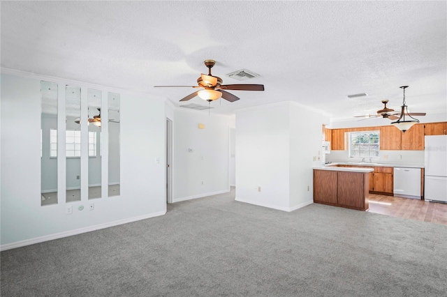 unfurnished living room featuring light carpet, a textured ceiling, and ornamental molding