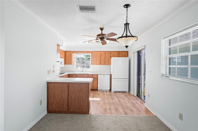 kitchen with pendant lighting, white appliances, sink, a textured ceiling, and kitchen peninsula