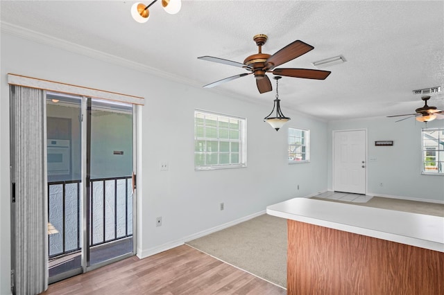 kitchen featuring decorative light fixtures, ceiling fan, light wood-type flooring, and a textured ceiling