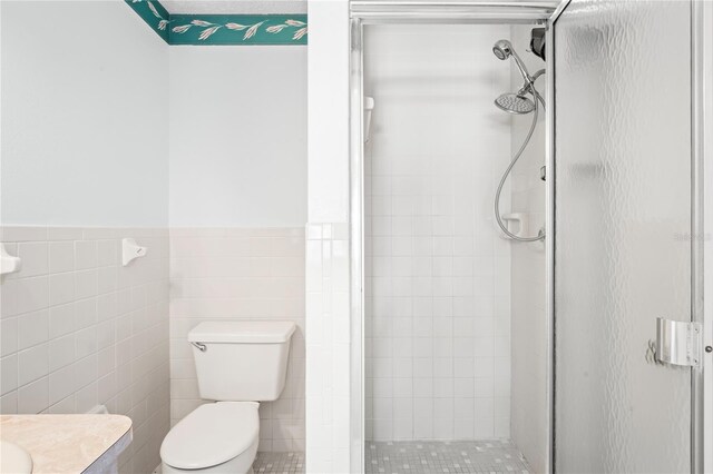 bathroom featuring vanity, toilet, an enclosed shower, and tile walls