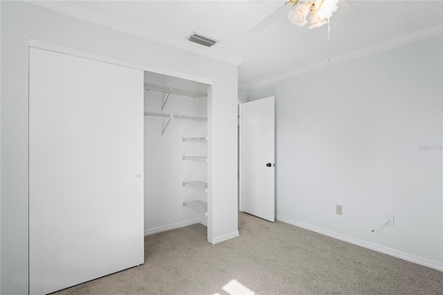 unfurnished bedroom with ceiling fan, ornamental molding, light carpet, and a closet