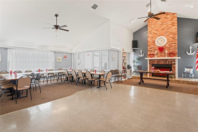 dining area with ceiling fan, a fireplace, and high vaulted ceiling