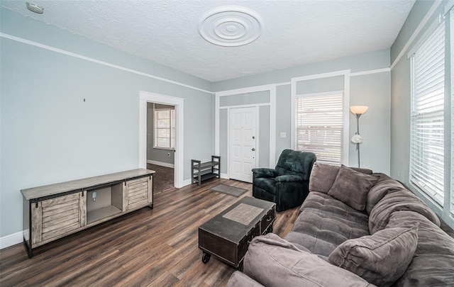 living room featuring dark wood-type flooring, a healthy amount of sunlight, and a textured ceiling