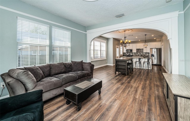 living room featuring a notable chandelier, a textured ceiling, and dark wood-type flooring