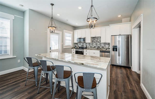 kitchen featuring a healthy amount of sunlight, appliances with stainless steel finishes, hanging light fixtures, and white cabinetry