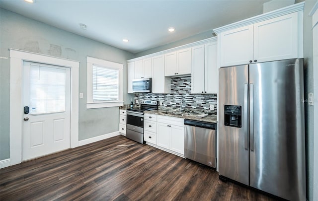 kitchen with appliances with stainless steel finishes, white cabinets, tasteful backsplash, and dark hardwood / wood-style flooring