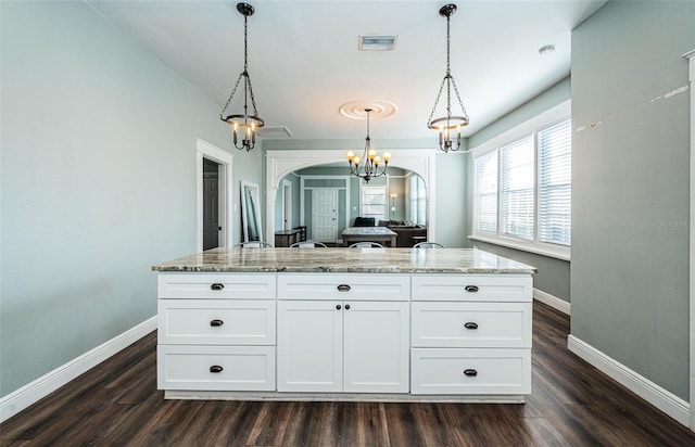 kitchen with white cabinetry, light stone counters, dark wood-type flooring, and pendant lighting