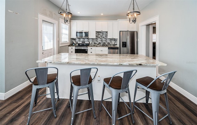 kitchen featuring stainless steel appliances, decorative backsplash, pendant lighting, and white cabinets