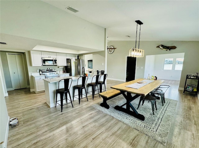 dining space featuring lofted ceiling and light hardwood / wood-style flooring