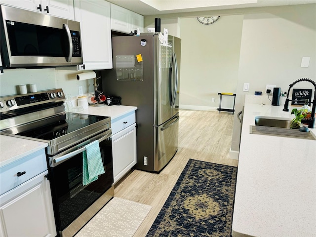 kitchen featuring light hardwood / wood-style flooring, appliances with stainless steel finishes, sink, and white cabinets