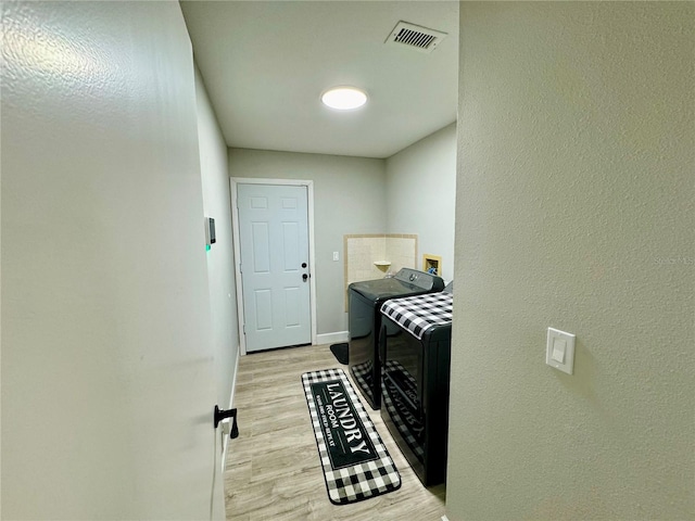 washroom with washing machine and dryer and light wood-type flooring