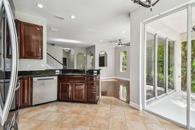 kitchen featuring dark stone countertops, sink, light tile patterned floors, stainless steel dishwasher, and ceiling fan