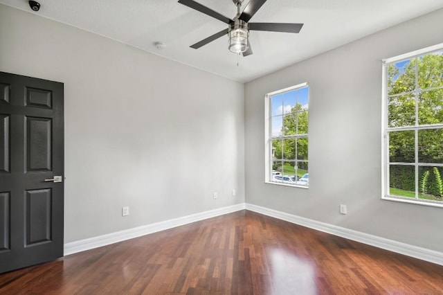 empty room featuring dark wood-type flooring and ceiling fan