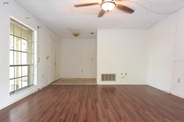 empty room featuring ceiling fan, plenty of natural light, and dark hardwood / wood-style floors