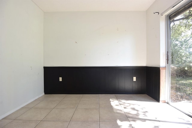 tiled spare room featuring wood walls