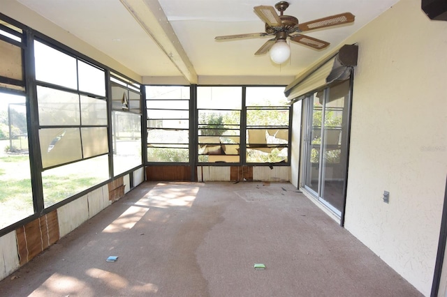 unfurnished sunroom featuring beamed ceiling and ceiling fan