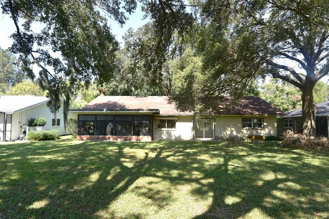 rear view of property featuring a lawn and a sunroom