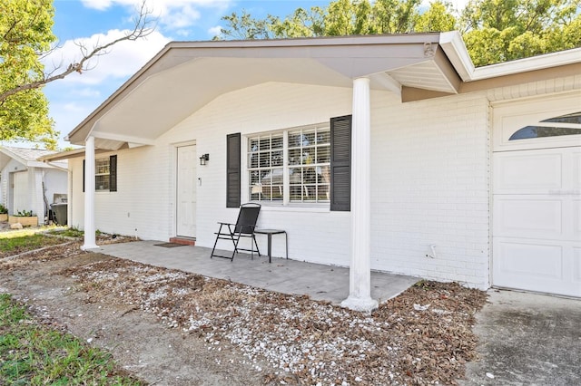 7240 Nova Scotia Dr, Port Richey, FL 34668 - doorway to property featuring brick siding, covered porch, and an attached garage