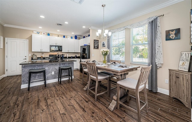 dining space featuring ornamental molding, an inviting chandelier, dark hardwood / wood-style floors, and sink