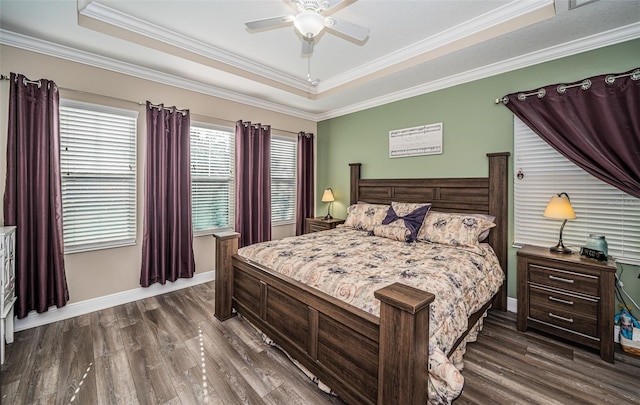 bedroom with crown molding, a tray ceiling, dark wood-type flooring, and ceiling fan