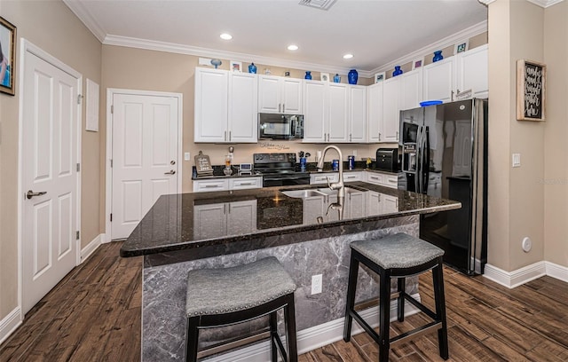 kitchen with a breakfast bar area, a kitchen island with sink, ornamental molding, dark hardwood / wood-style floors, and black appliances