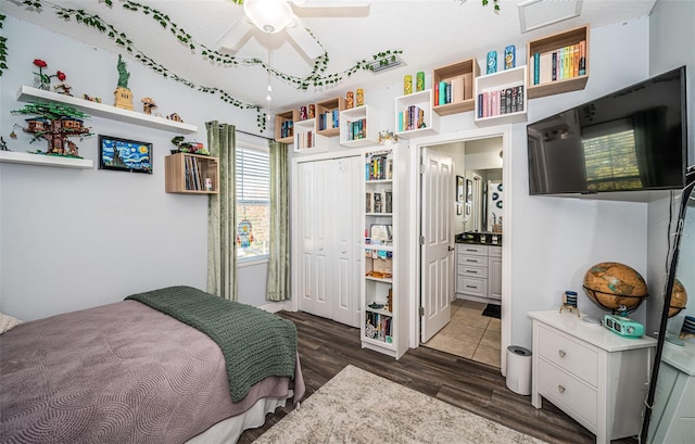 bedroom featuring connected bathroom, dark wood-type flooring, a closet, and ceiling fan