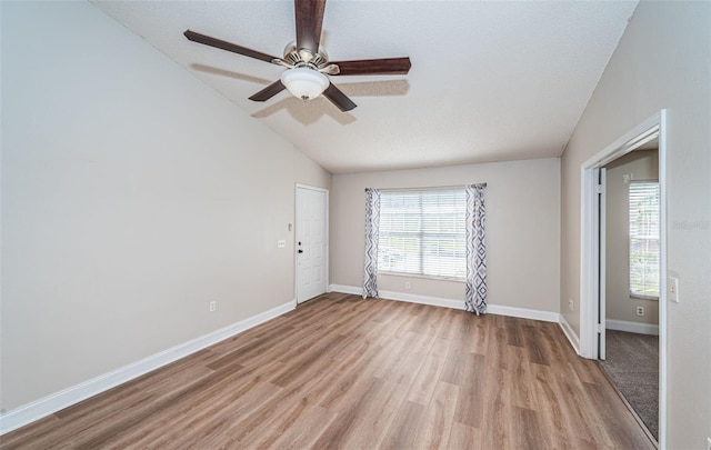 empty room with light hardwood / wood-style floors, a textured ceiling, ceiling fan, and vaulted ceiling