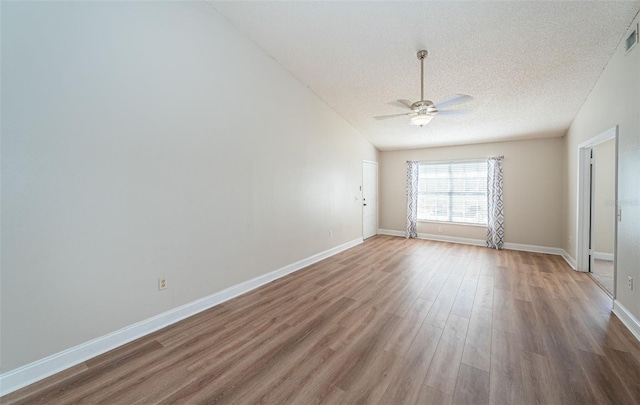 spare room with lofted ceiling, hardwood / wood-style floors, a textured ceiling, and ceiling fan