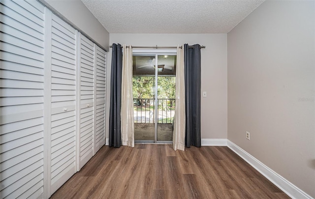 unfurnished bedroom featuring a textured ceiling and dark hardwood / wood-style floors