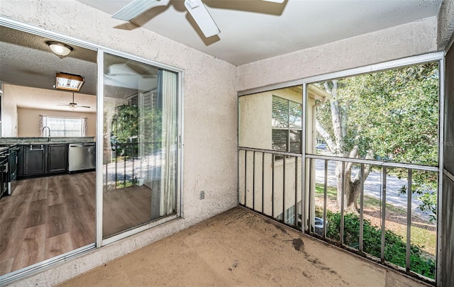 unfurnished sunroom featuring sink and ceiling fan