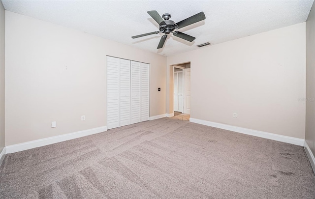 unfurnished bedroom with a closet, carpet floors, a textured ceiling, and ceiling fan