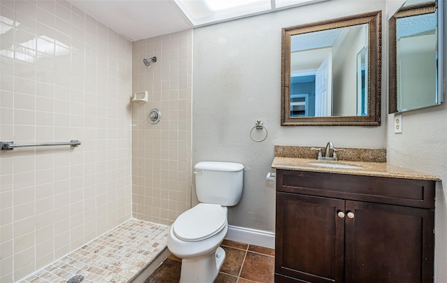 bathroom featuring vanity, tiled shower, toilet, and tile patterned flooring