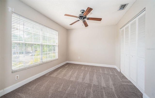 unfurnished bedroom with carpet, a textured ceiling, a closet, and ceiling fan