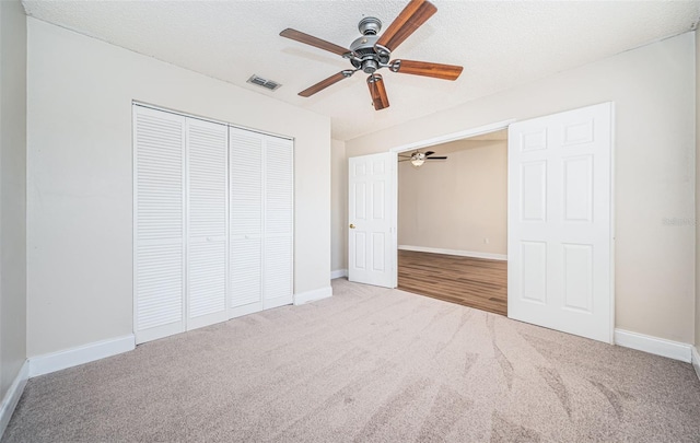 unfurnished bedroom with a closet, carpet floors, a textured ceiling, and ceiling fan