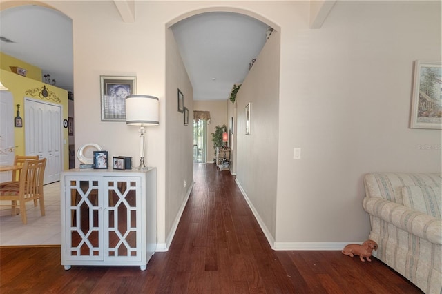 corridor featuring beam ceiling and dark wood-type flooring