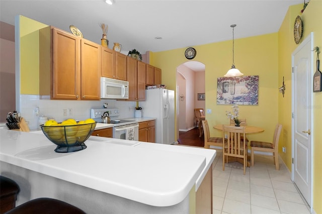 kitchen featuring kitchen peninsula, tasteful backsplash, pendant lighting, and white appliances