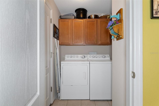 clothes washing area with light tile patterned flooring, separate washer and dryer, and cabinets