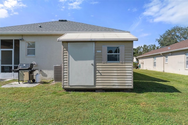 back of house with a storage unit, cooling unit, and a lawn