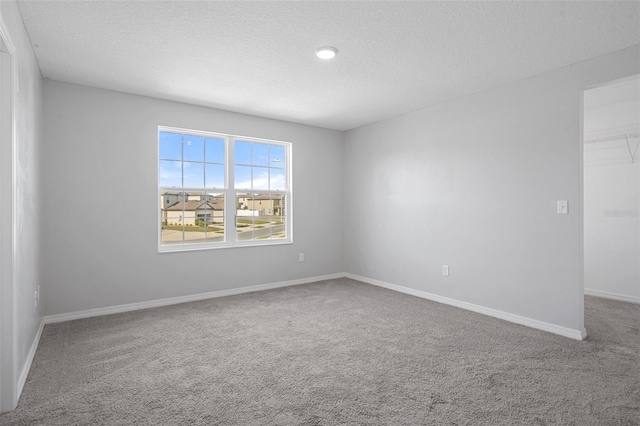 empty room with carpet flooring and a textured ceiling