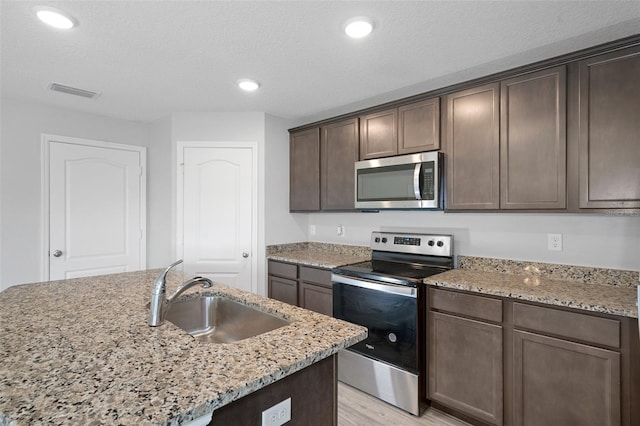 kitchen featuring light stone counters, sink, stainless steel appliances, and light hardwood / wood-style flooring