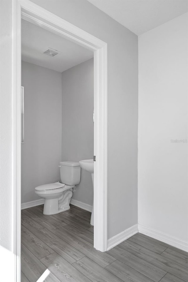 bathroom with hardwood / wood-style flooring and toilet