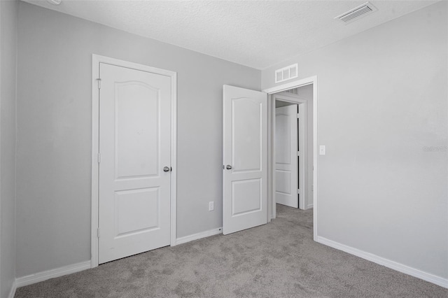 unfurnished bedroom with light carpet and a textured ceiling