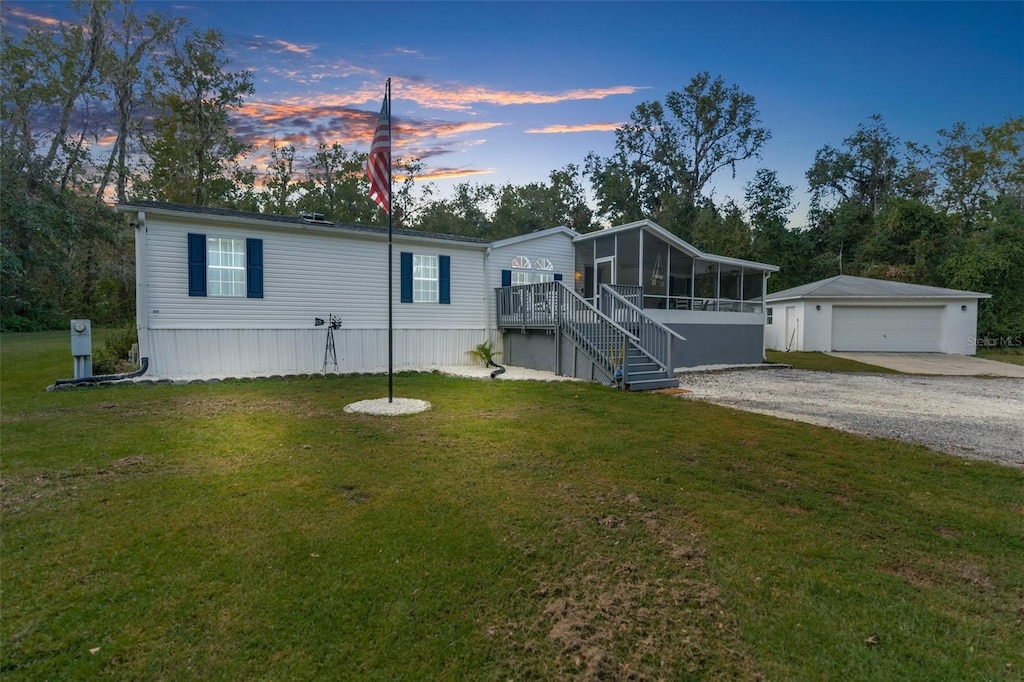 manufactured / mobile home with a yard, a sunroom, an outbuilding, and a garage