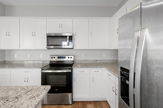 kitchen featuring white cabinetry, light hardwood / wood-style flooring, light stone countertops, and appliances with stainless steel finishes