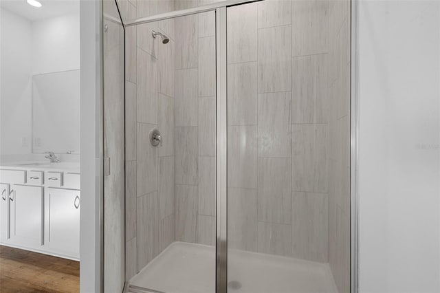 bathroom with hardwood / wood-style floors, vanity, and an enclosed shower